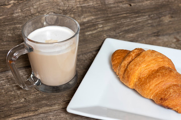 French breakfast with croissant and cappuccino over wooden background