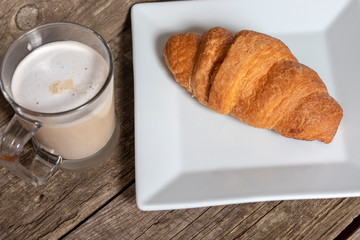 French breakfast with croissant and cappuccino over wooden background