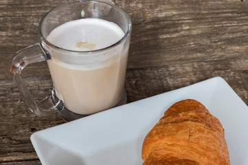 French breakfast with croissant and cappuccino over wooden background