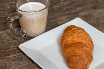 French breakfast with croissant and cappuccino over wooden background