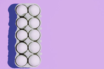 White chicken eggs in a cardboard package with empty space, on a blue background
