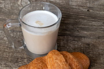 French breakfast with croissant and cappuccino over wooden background