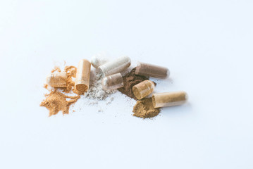 Herbal pills. Open capsules and powder on white background