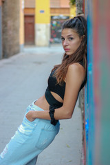 Trendy beautiful long haired young model posing on graffiti background