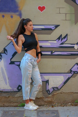 Trendy beautiful long haired young model posing on graffiti background