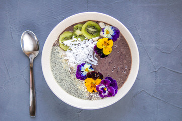 Healthy breakfast bowl with smoothie, fruit, seeds, coconut and edible flowers