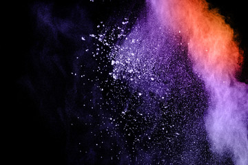 Purple orange color powder explosion cloud  on black background.Closeup of purple orange dust...