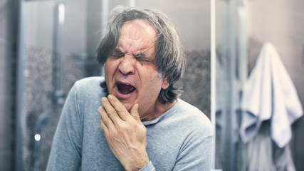 Mature man yawning in bathroom