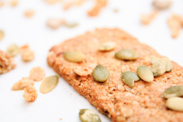 muesli cookies sprinkled with pumpkin seeds, isolated on a white background, selective focus. Top view