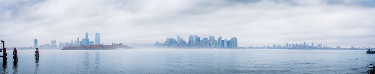 Fototapeta na wymiar Panoramic New York City skyline with dramatic low clouds including Jersey City, Manhattan, and Brooklyn as seen from Liberty Island