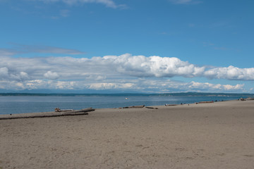 Fototapeta na wymiar Sandy beach with blue water, sky and clouds