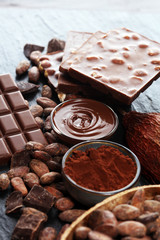 Melting chocolate or melted chocolate with a chocolate swirl and stack, chips and powder on black