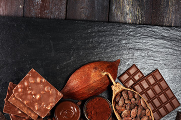 Melting chocolate or melted chocolate with a chocolate swirl and stack, chips and powder on black