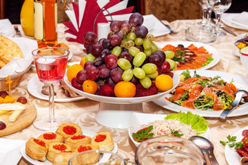 Luxurious table setting for a wedding or a holiday with beautiful fresh fruits and berries in a vase