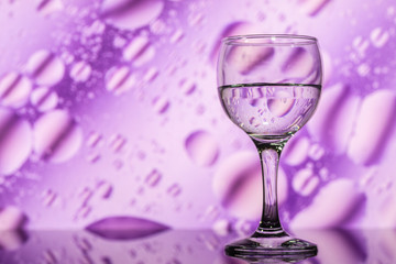transparent glass with water and oily drops on background 