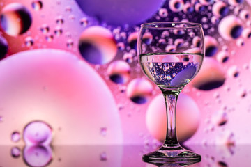 ransparent glasses with water and oily drops on colorful background 