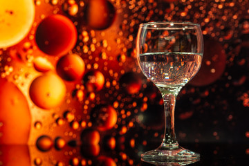 ransparent glasses with water and oily drops on colorful background 