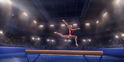 Female athlete doing a complicated exciting trick on gymnastics balance beam in a professional gym....
