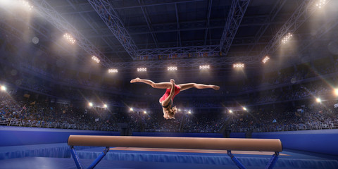 Female athlete doing a complicated exciting trick on gymnastics balance beam in a professional gym....