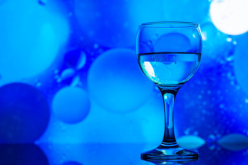 transparent glasses with water and oily drops on colorful background 