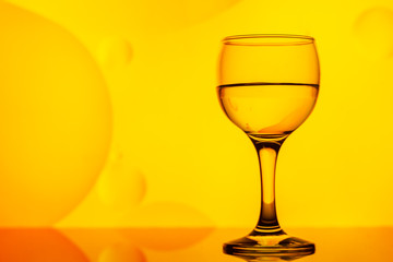 transparent glasses with water and oily drops on colorful background 