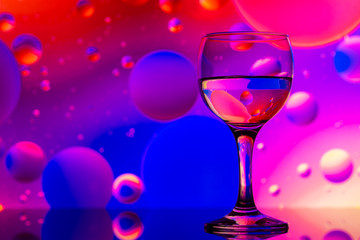 transparent glasses with water and oily drops on colorful background 