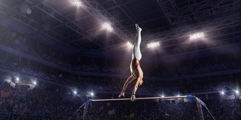 Male athlete doing a complicated exciting trick on horizontal gymnastics bars in a professional...