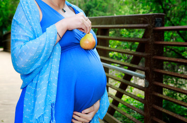 Pregnant woman holds a pear as symbol of organic food for healthy baby.