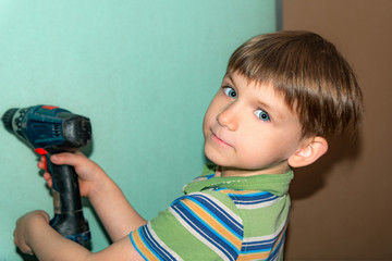 A boy with a screwdriver looks into the camera while working and repairing a eurodepartment.