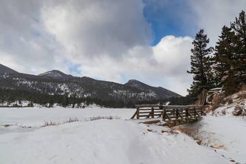 Fototapeta na wymiar Wooden footbridge at frozen Lily Lake, Rocky Mountains National Park Colorado