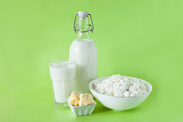 milk in a bottle cottage cheese butter and a glass of milk on a green background