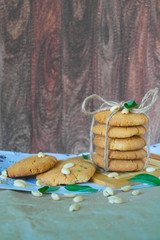 A stack of peanut cookies tied with a harness on a stand. on the table are nuts and green leaves