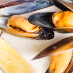 plate with boiled mussels in armor with lemon pieces