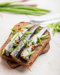 sprats with spices and herbs on a piece of dark bread