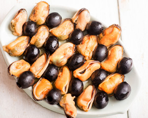 mussels and olives as an appetizer to white wine on a light background