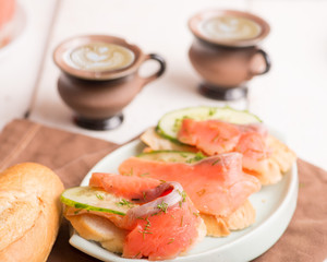breakfast with salmon slices with microgreen and cucumber and cups of coffee