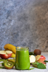 Green smoothie with banana, kiwi, apple and spinach on a concrete background. Detox menu.
