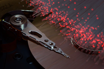Close-up on opened computer hard disk drive with colored optic fiber.