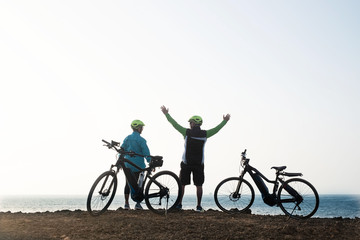 Obraz premium Two people enjoy the view of the ocean resting after an excursion with the bicycles. Cliff of volcanic landscape