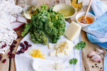 Ingridients on the kitchen for salad. Parmesan. Honey. Cranberries. Arugula. Cabbage. Oil. Wooden.