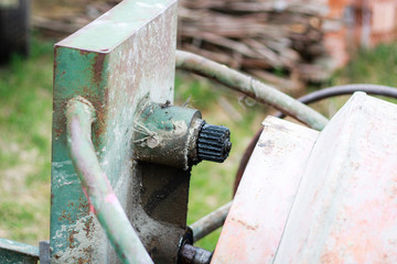 A man repairs a hand-held concrete mixer. Bearing lubrication.