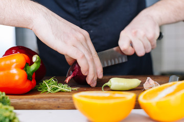 Chef cut onion and vegetables. Wooden. Kitchen. Healthy food. Raw.