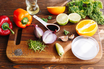 Raw ingridients. Kitchen. Wooden table. Pepper, spices, onion garlic, orange, cabbage, seeds chia, lime. Sun light. Healthy food. Vegetables. Diet. Oil. Morning.
