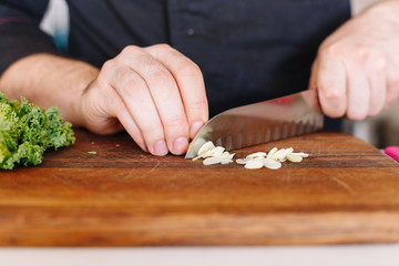 Chef cut garlic and vegetables. Wooden. Kitchen. Healthy food. Raw.