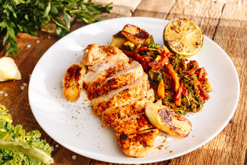 Grilled chicken with spices and baked vegetables. Carrot. Lime. Banana. Dish. Wooden. Ingridients. Kitchen. Homemade. Dish with meat. Lunch. Dinner.