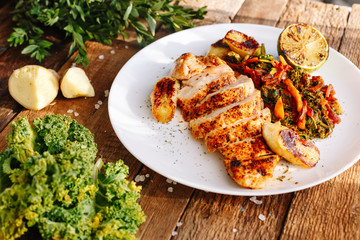 Grilled chicken with spices and baked vegetables. Carrot. Lime. Banana. Dish. Wooden. Ingridients. Kitchen. Homemade. Dish with meat. Lunch. Dinner.