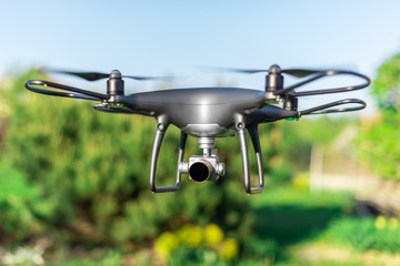 Dark drone flying through the air in the sun.