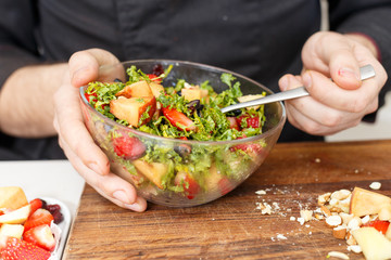 chef making salad with berries, cheese and honey. strawberry. process. cook hands. wooden. nuts.
