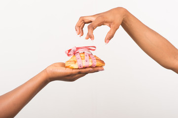 two woman hands holding a cake with measuring tape isolated on white background.