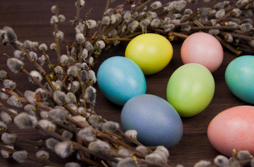 Fototapeta na wymiar colorful easter eggs and willow wreath on wooden background
